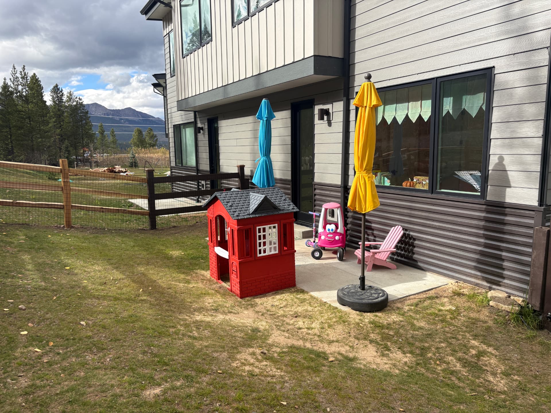 The El Nidito backyard with a red playhouse, colorful umbrellas, and mountain views